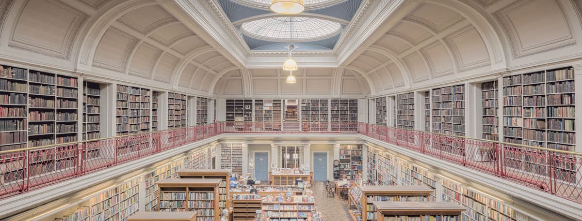 The long, light-filled library of the Literary and Philosophical Society in Newcastle, with a galleried upper floor of bookcases beneath a domed skylight
