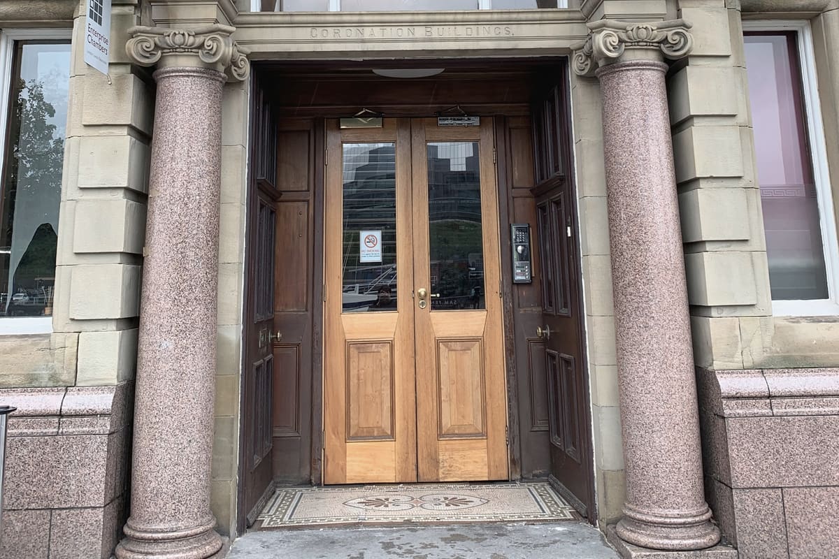 The carved stone doorway of Coronation Buildings on Newcastle Quayside, with polished granite columns and panelled doors