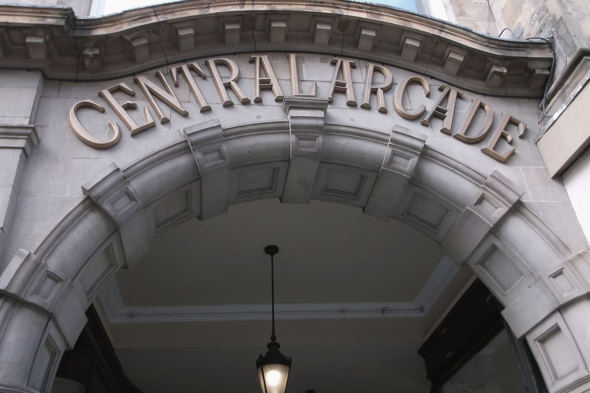 The carved stone entrance arch of Central Arcade in Newcastle, with its name in raised letters and a lantern hanging below