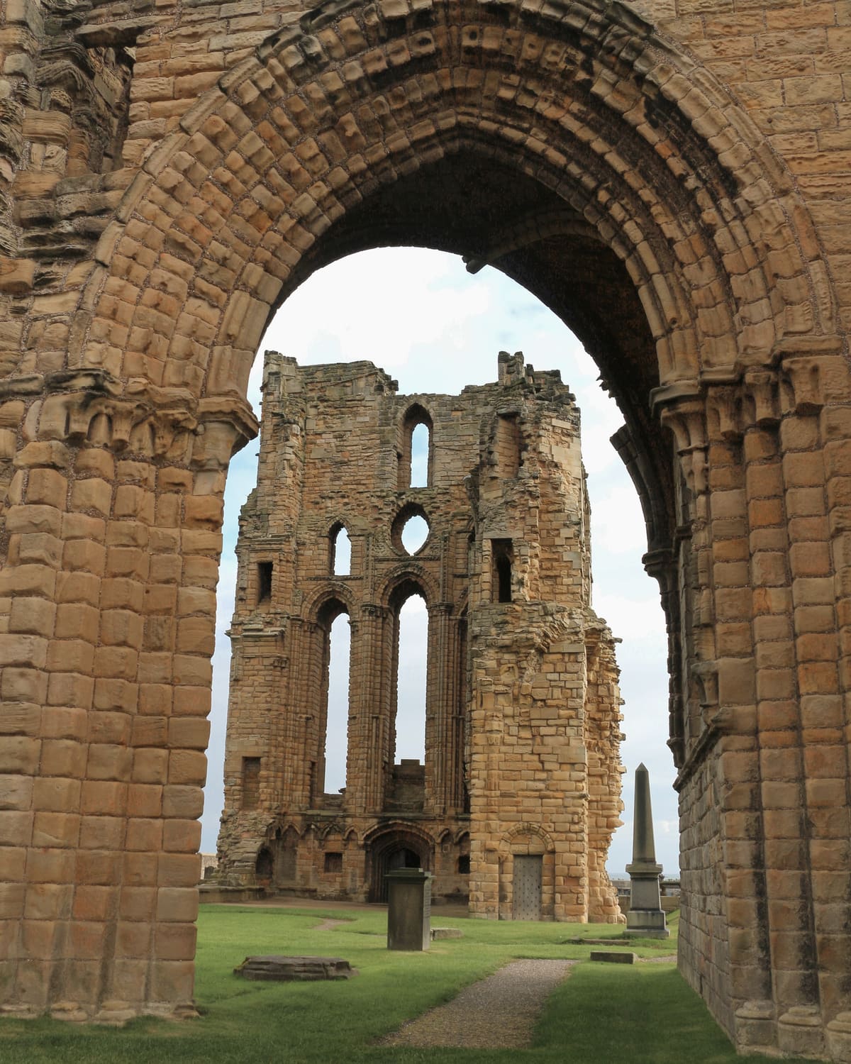 The ruined east end of Tynemouth Priory framed by a weathered Norman stone arch